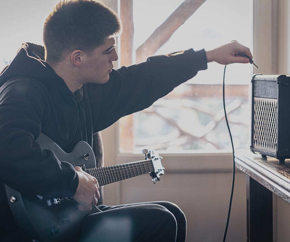 image of man plugging in guitar that he bought at WestSide Music.